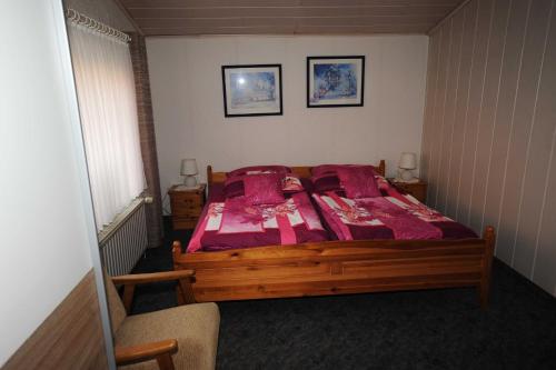 a bedroom with a wooden bed with red sheets at Ferienwohnung Frieda, 65207 in Moormerland