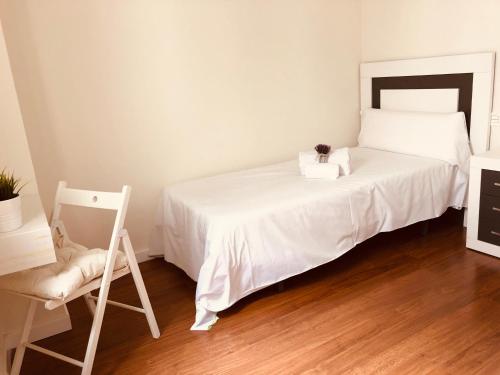 a bedroom with a white bed and a chair at Apartamento turisticos Puente Romano P3 2-B in Salamanca