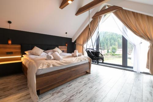 a bedroom with a large bed and a large window at Apartamenty Marron z sauną, bawialnią i widokiem na Skrzyczne - Dream Apart in Szczyrk