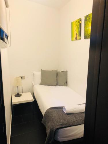 a small bedroom with a white bed and a lamp at Barcelona Fifteen central Aparthotel in Barcelona