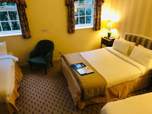 a hotel room with two beds and a chair at Marston Farm Hotel in Sutton Coldfield