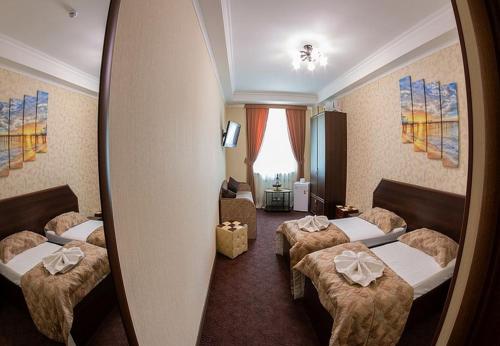 una camera d'albergo con tre letti e uno specchio di Oscar Mini Hotel a Sinferopoli