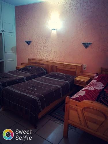 a bedroom with two beds and a light on the wall at Résidence Loued in Tozeur