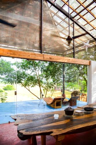 a wooden table in a room with a large window at Seclude Falling Cashews, Chorao Island, North Goa in Chorao