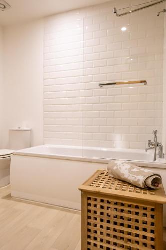 a white bathroom with a tub and a toilet at Cavernous open plan town house in st Leonards in St. Leonards
