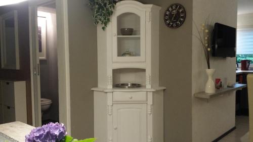 a white cabinet in a room with a clock at Logis Am Park in Dessau