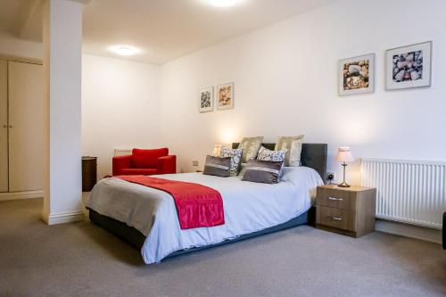 a bedroom with a large bed and a red chair at Cavernous open plan town house in st Leonards in St. Leonards