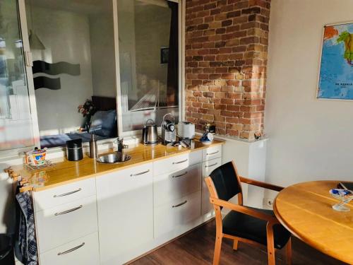 a kitchen with white cabinets and a table and a brick wall at Imagine My B&B in Rotterdam