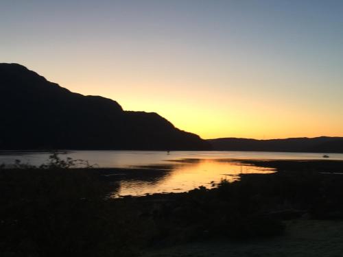 a sunset over a body of water with mountains at Rowan House B&B Rooms & A Self Catering Apartment in Lochgoilhead