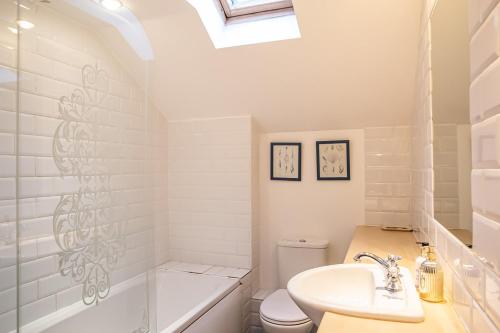 a bathroom with a sink and a toilet and a bath tub at Stylish modern Mews house in central St Leonards in Hastings