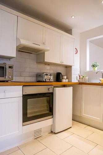 a kitchen with white cabinets and a stove top oven at Stylish modern Mews house in central St Leonards in Hastings