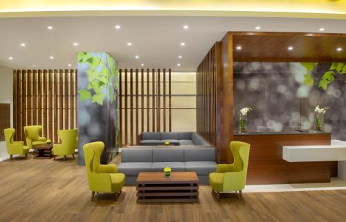a lobby with a blue couch and green chairs at Wyndham Garden Muscat Al Khuwair in Muscat