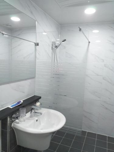 a white bathroom with a sink and a shower at Seong Dong Jang in Daegu