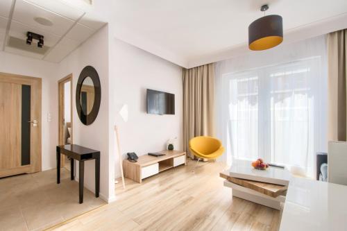 a living room with white walls and a yellow chair at Varsovia Apartamenty Kasprzaka in Warsaw