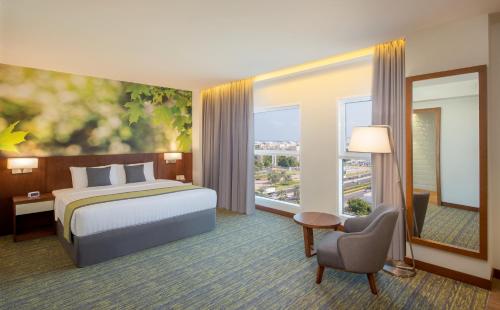 a hotel room with a bed and a large window at Wyndham Garden Muscat Al Khuwair in Muscat