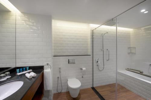 a bathroom with a shower and a toilet and a sink at Wyndham Garden Muscat Al Khuwair in Muscat