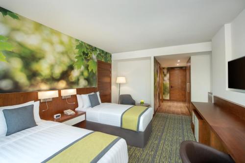 a hotel room with two beds and a television at Wyndham Garden Muscat Al Khuwair in Muscat