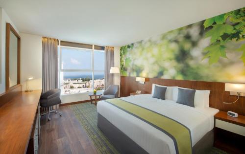 a hotel room with a bed and a large window at Wyndham Garden Muscat Al Khuwair in Muscat