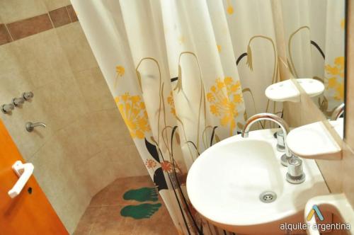 Un baño con lavabo y cortina de ducha. en Departamentos Las Marias, en Villa Cura Brochero
