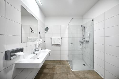 uma casa de banho branca com um lavatório e um chuveiro em Hotel Gasthof-Strasser em Tumeltsham