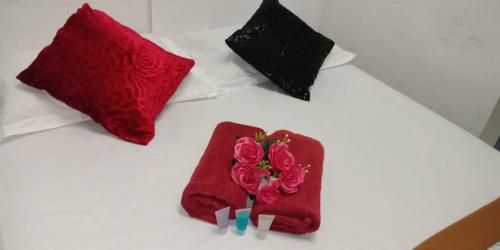 a bed with red and black pillows and flowers on it at Weng Kong Hotel in Slim River