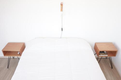 1 cama blanca con 2 mesitas de noche de madera en Departamento Aeropuerto Circunvalacion Kempes Quorum -cambio oficial- en Córdoba