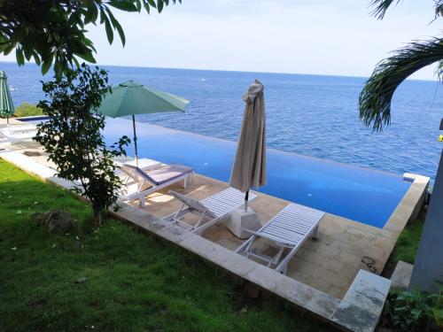 a pool with two chairs and an umbrella at Villa Infinite Horizon in Amed