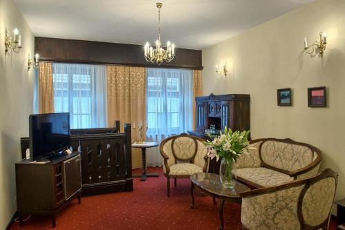 a living room with a tv and a table and chairs at Hotel Dwór Polski in Wrocław
