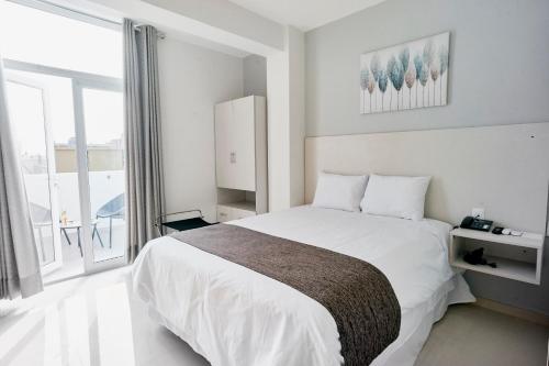 Un dormitorio con una cama blanca y una ventana grande. en Anturio Hotel, en Trujillo