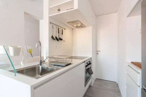 a white kitchen with a sink and a counter at Beautiful Apartment with View of the Tagus River in Lisbon