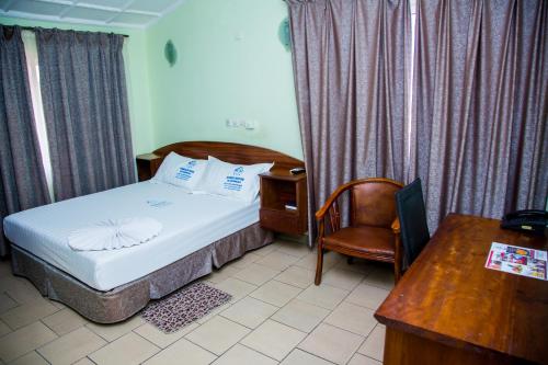 a bedroom with a bed and a desk and a chair at Résidence Hôtelière de Moungali in Brazzaville