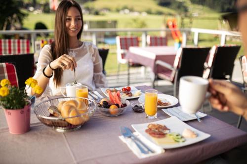 a woman sitting at a table with a plate of food at Hotel Wildauerhof in Walchsee