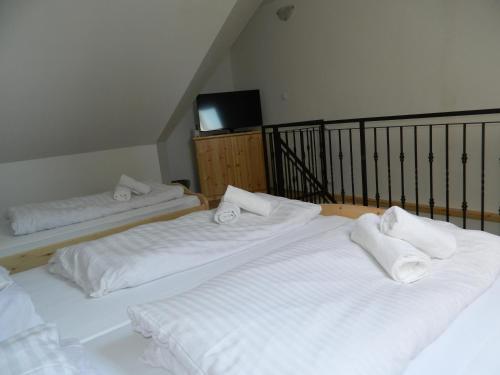 - 2 lits dans une chambre avec des draps blancs et des serviettes dans l'établissement Família-Pelso apartmanház, à Zamárdi