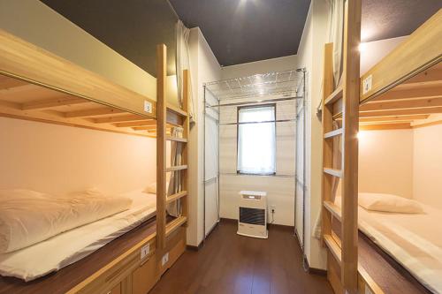 a room with two bunk beds and a window at Guesthouse Nibutani Yanto in Biratori