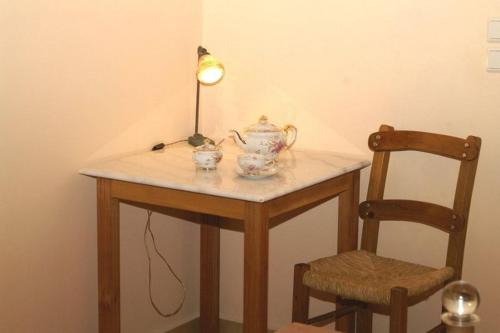 a table with a tea pot and a lamp and a chair at Sarris House in Xirokámbion