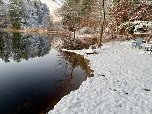 a snow covered lake with two chairs next to it at Clear Pond Suite in Plymouth
