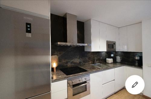 a kitchen with white cabinets and a stainless steel refrigerator at Mirador Del Río Piedra in Nuévalos