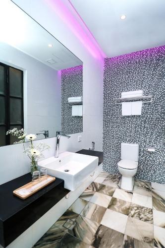 a bathroom with a sink and a toilet and a mirror at Macalister Terraces Hotel in George Town