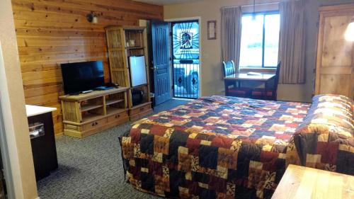 Habitación de hotel con cama y TV en Chama River Bend Lodge, en Chama