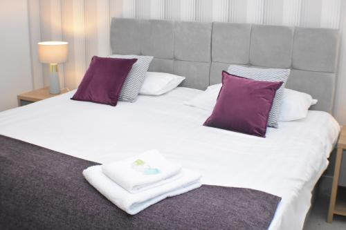 a bedroom with a large bed with purple and white pillows at Four Chimneys House in Peterborough