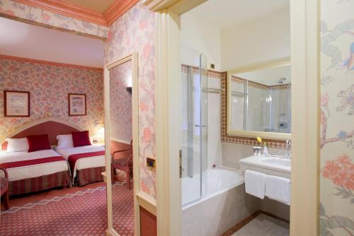 ミラノにあるHotel Milano Regencyのベッドルーム1室(ベッド1台、バスタブ、シンク付)