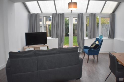 a living room with a couch and a tv at Four Chimneys House in Peterborough