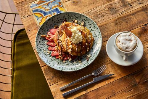 a plate of pancakes and strawberries next to a cup of coffee at Hotel Indigo Madrid - Princesa by IHG in Madrid