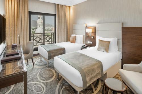 a hotel room with two beds and a balcony at Millennium Makkah Al Naseem in Makkah