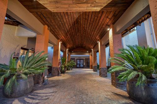 a hallway with potted plants and a wooden ceiling at Villa Bali Luxury Guesthouse in Bloemfontein