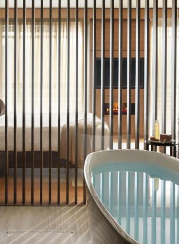 a bedroom with a tub and a bed with a bed sqor at Lefay Resort & SPA Dolomiti in Pinzolo