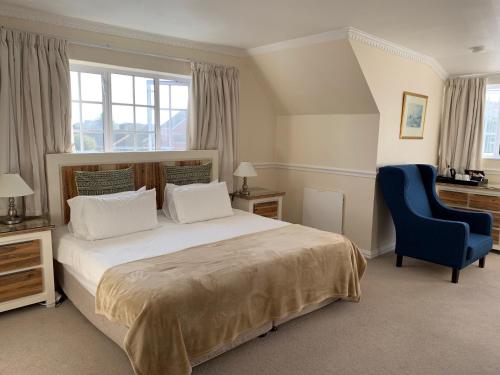 a bedroom with a large bed and a blue chair at Birkenhead Manor in Bloubergstrand