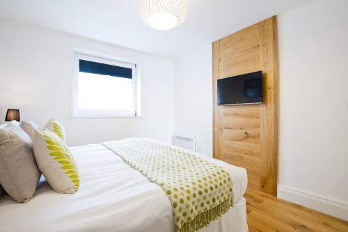 a white bedroom with a bed and a window at 27 The Terrace in St Ives