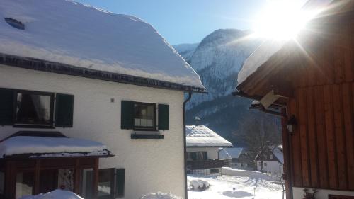 a building with snow on the roof and the sun at Haus 66 in Obertraun
