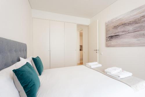 a white bedroom with a large bed with green pillows at FLH Chiado Central Flat in Lisbon